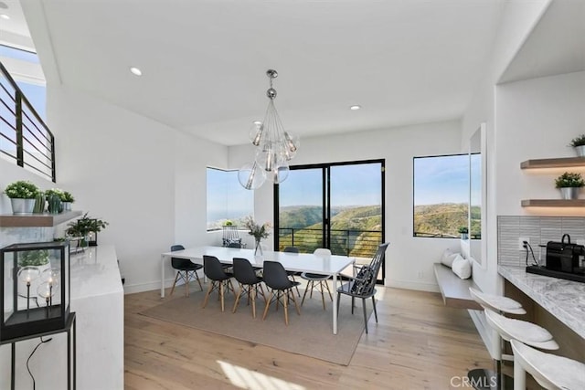 dining space with a mountain view, an inviting chandelier, and light hardwood / wood-style flooring