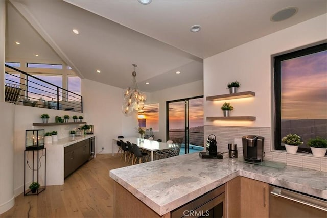kitchen featuring backsplash, open shelves, dishwasher, a notable chandelier, and light wood-style floors