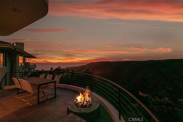 balcony at dusk featuring a fire pit