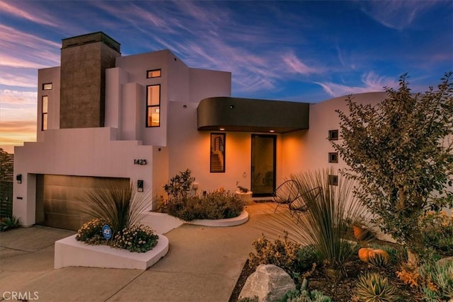 view of front of house with driveway, an attached garage, and stucco siding