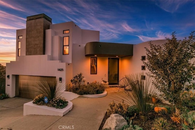 view of front facade featuring concrete driveway, an attached garage, and stucco siding