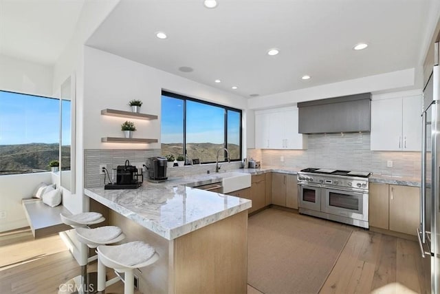 kitchen featuring a peninsula, double oven range, a sink, and plenty of natural light