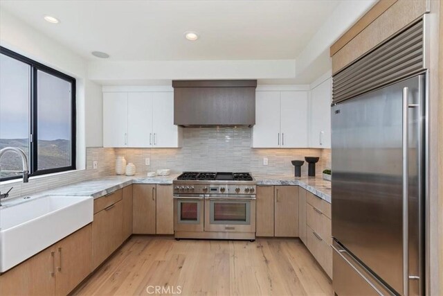 1425 Skyline Dr, Laguna Beach, CA 92651 - kitchen featuring high quality appliances, custom range hood, light wood-style floors, backsplash, and white cabinetry