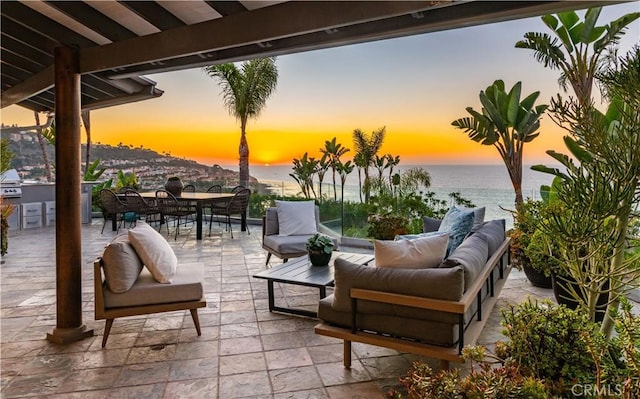 patio terrace at dusk featuring a water view, area for grilling, a grill, and an outdoor hangout area