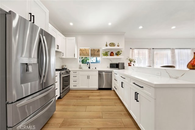 kitchen featuring appliances with stainless steel finishes, white cabinets, light hardwood / wood-style floors, kitchen peninsula, and light stone countertops