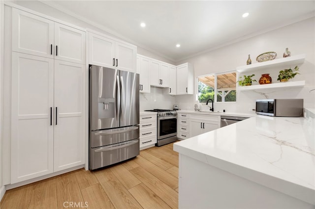 kitchen with stainless steel appliances, light stone countertops, sink, and white cabinets