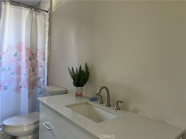 bathroom with toilet, vanity, and curtained shower