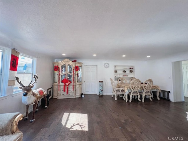 unfurnished dining area featuring dark hardwood / wood-style flooring, a textured ceiling, and radiator heating unit