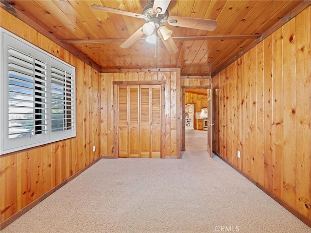 spare room with carpet flooring, wood ceiling, and wooden walls