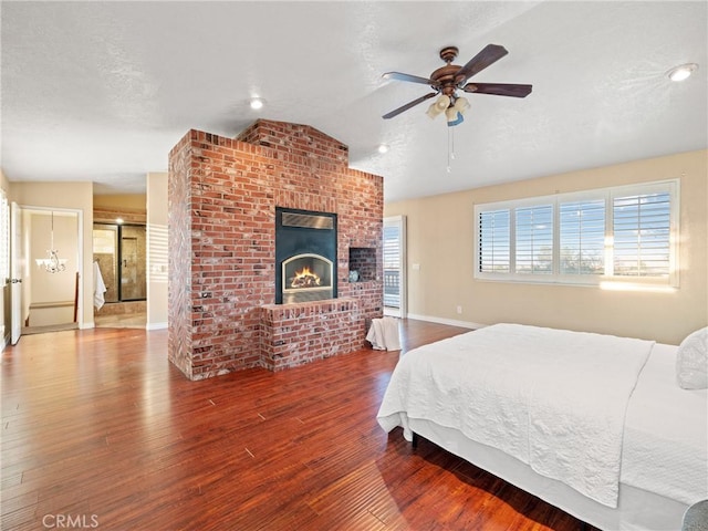 bedroom with vaulted ceiling, hardwood / wood-style floors, ceiling fan, a brick fireplace, and a textured ceiling