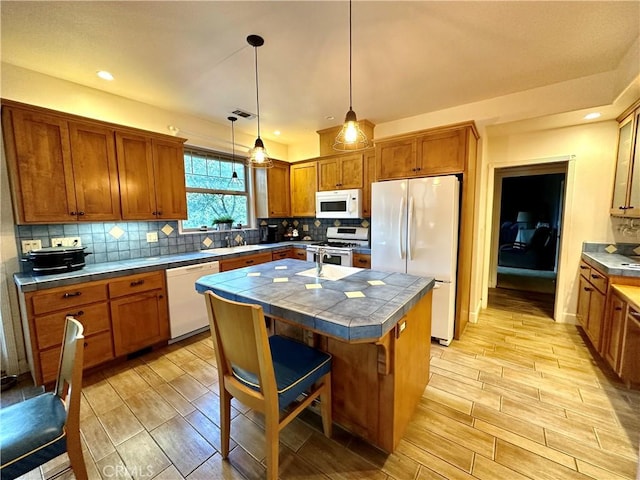 kitchen featuring pendant lighting, white appliances, a breakfast bar, a kitchen island, and decorative backsplash