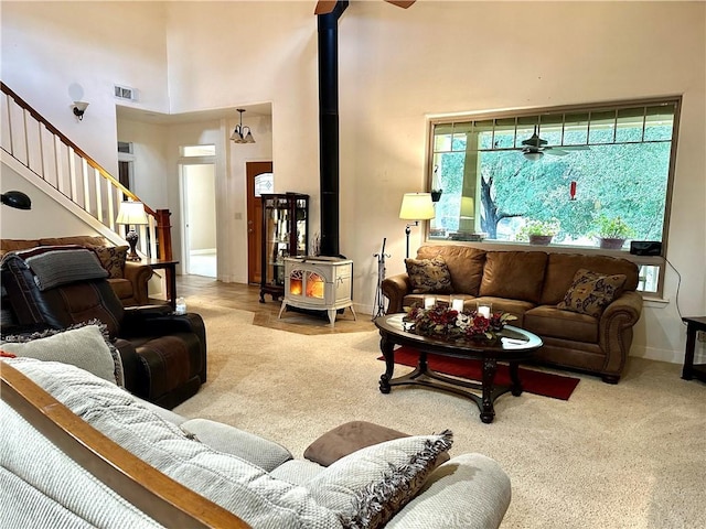 living room featuring carpet flooring, a high ceiling, and a wood stove