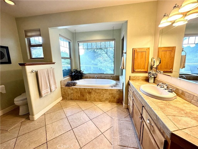 bathroom featuring tiled tub, vanity, tile patterned floors, and toilet