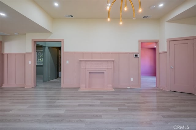 unfurnished living room with a chandelier and light wood-type flooring