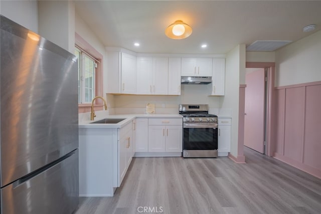 kitchen with stainless steel appliances, white cabinetry, sink, and light hardwood / wood-style floors