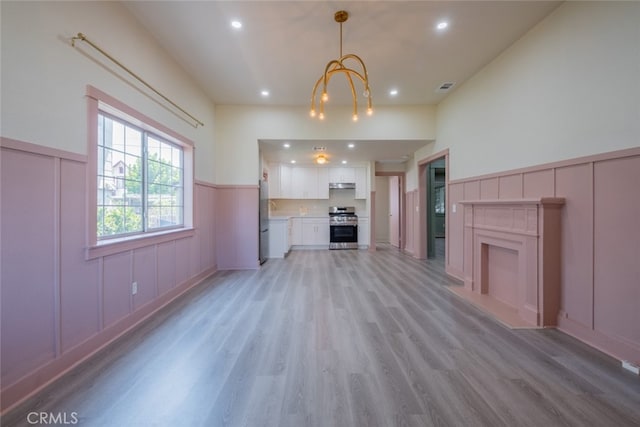 unfurnished living room with a notable chandelier and light wood-type flooring