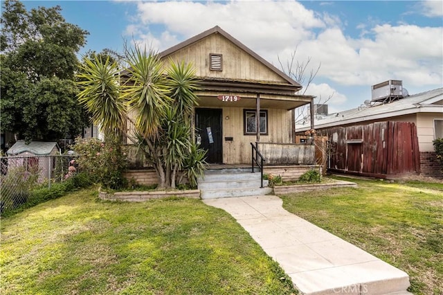 bungalow-style home featuring a porch, cooling unit, and a front lawn