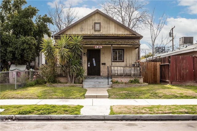 bungalow featuring covered porch, a front yard, and central air condition unit