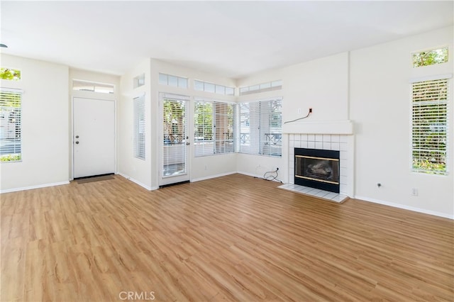 unfurnished living room with a tile fireplace and light hardwood / wood-style floors