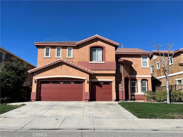 mediterranean / spanish house with a garage, stucco siding, concrete driveway, and a tile roof