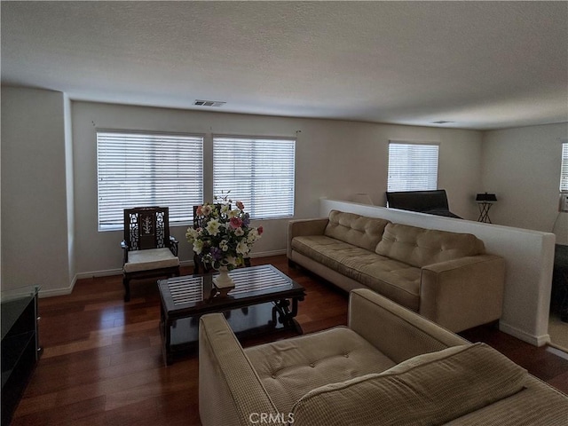 living area with wood finished floors, baseboards, and visible vents