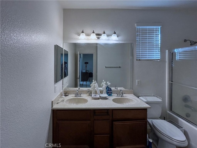 bathroom with double vanity, a textured wall, a sink, and enclosed tub / shower combo