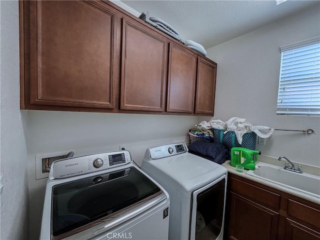washroom featuring washer and dryer, a textured ceiling, a sink, and cabinet space
