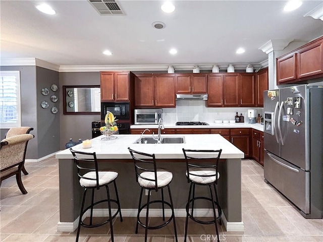 kitchen with ornamental molding, black appliances, under cabinet range hood, visible vents, and a sink