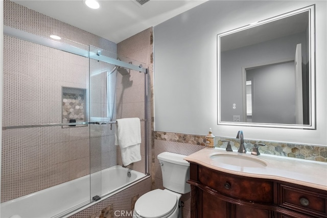 full bathroom featuring tile walls, vanity, enclosed tub / shower combo, and toilet