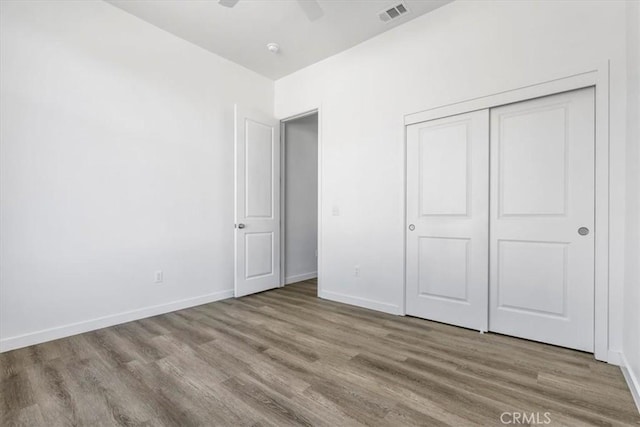 unfurnished bedroom with ceiling fan, a closet, and light wood-type flooring