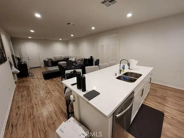 kitchen with sink, light hardwood / wood-style flooring, white cabinetry, an island with sink, and stainless steel dishwasher