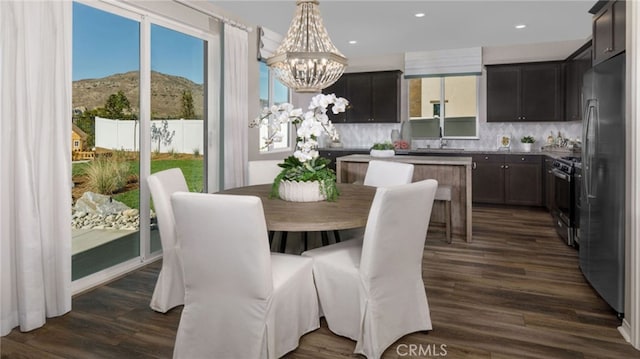 dining area with a mountain view, dark hardwood / wood-style floors, and an inviting chandelier