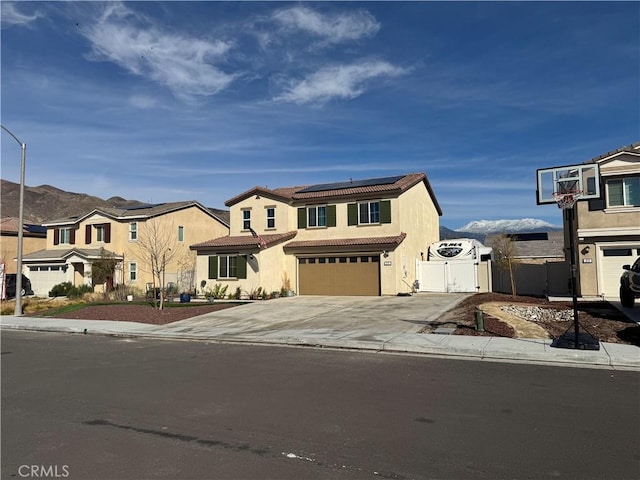 view of front of house with concrete driveway, roof mounted solar panels, stucco siding, a garage, and a gate