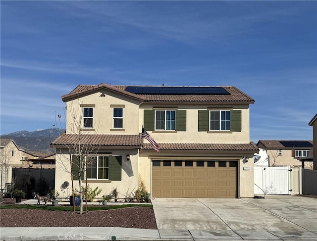 mediterranean / spanish home featuring a tiled roof, stucco siding, driveway, an attached garage, and a gate