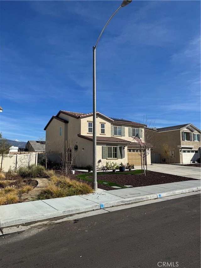 view of front facade featuring fence, driveway, stucco siding, a garage, and a tiled roof