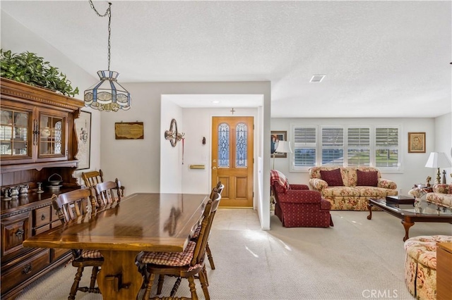 dining area with visible vents, a textured ceiling, and light colored carpet