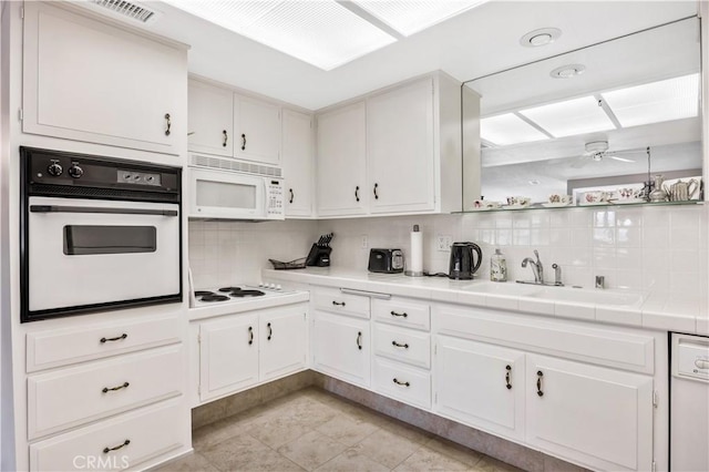 kitchen featuring visible vents, backsplash, a sink, ceiling fan, and white appliances