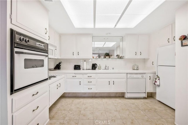 kitchen with light tile patterned floors, light countertops, white cabinets, a sink, and white appliances