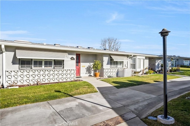 ranch-style home featuring a front yard and stucco siding