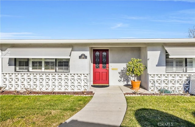 doorway to property with a yard and stucco siding