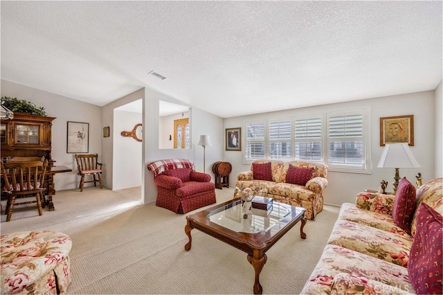 living area featuring carpet floors, visible vents, and a textured ceiling