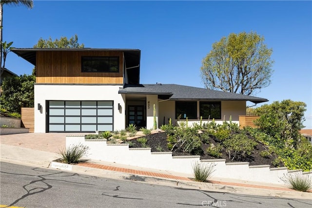 modern home featuring decorative driveway, a garage, and stucco siding