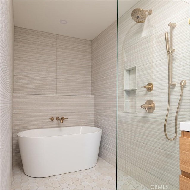 bathroom featuring tile patterned floors, a soaking tub, tile walls, and a tile shower