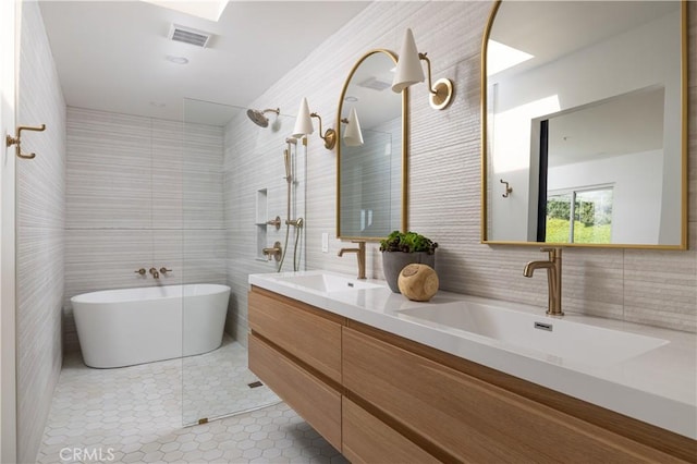 full bathroom featuring a sink, tile walls, a tile shower, and tile patterned flooring