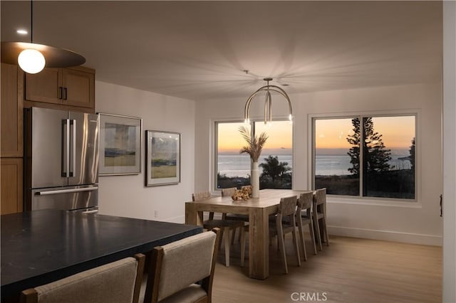 dining room with baseboards, light wood-type flooring, and a water view