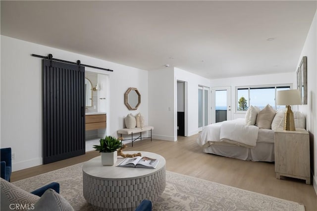 bedroom featuring baseboards, a barn door, and wood finished floors