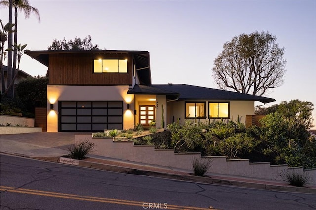 view of front of home with decorative driveway, a garage, and stucco siding