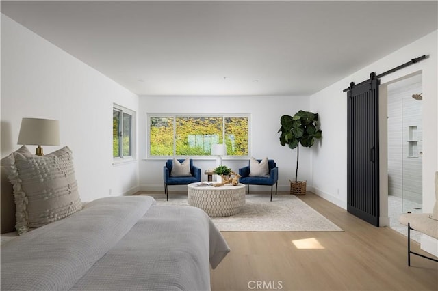 bedroom with a barn door, baseboards, and light wood-style floors