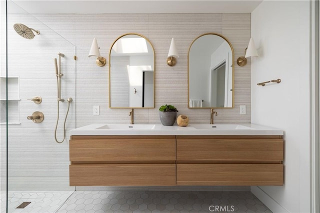 full bathroom with a sink, double vanity, and a tile shower