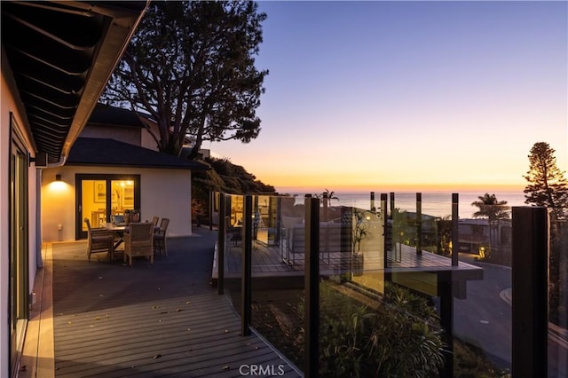 wooden terrace with a water view and outdoor dining space